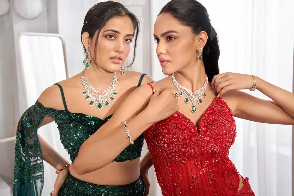 Two models, one in green and one in red, each wearing a statement diamond necklace