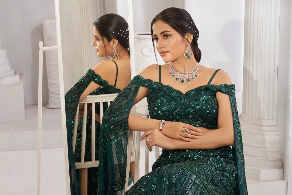 Model seated on a white chair beside a mirror, wearing a diamond necklace and earrings