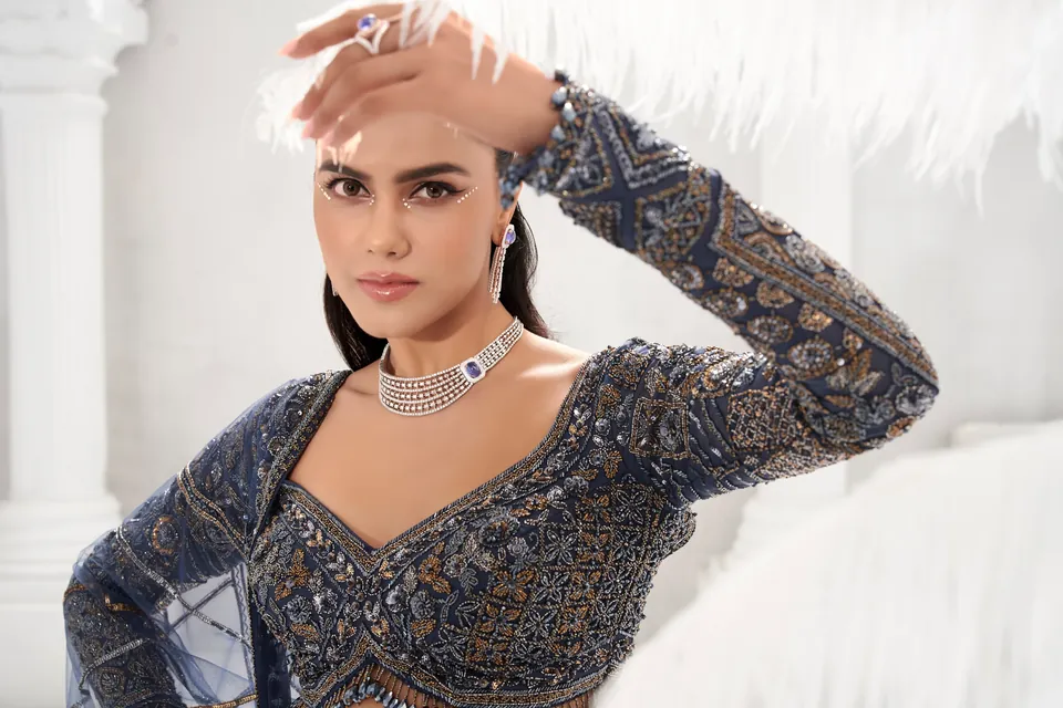 Model in a navy embroidered blouse, hand raised, wearing a diamond choker