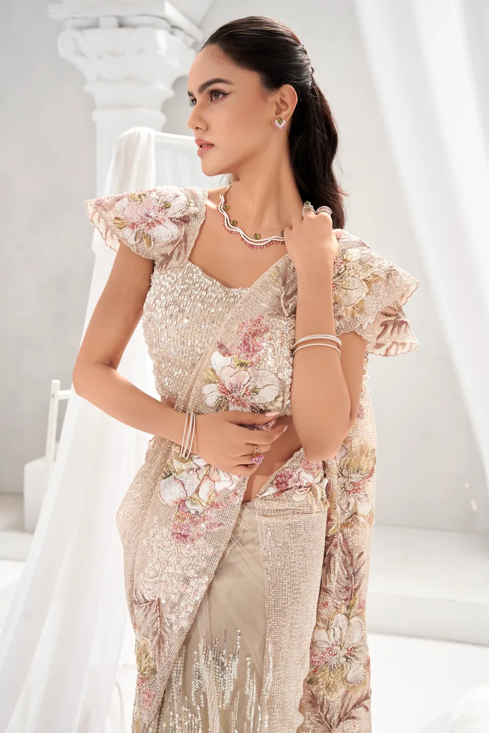 Full-length view of a champagne sequinned sari with floral appliqué and a fine necklace