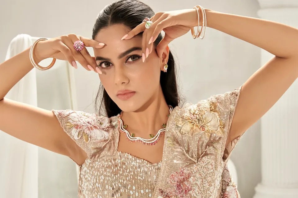 Model with hands raised to the face, showing rings and bangles