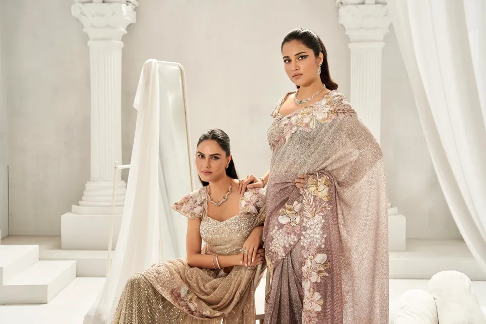 Two models in champagne and blush saris posed between white pillars