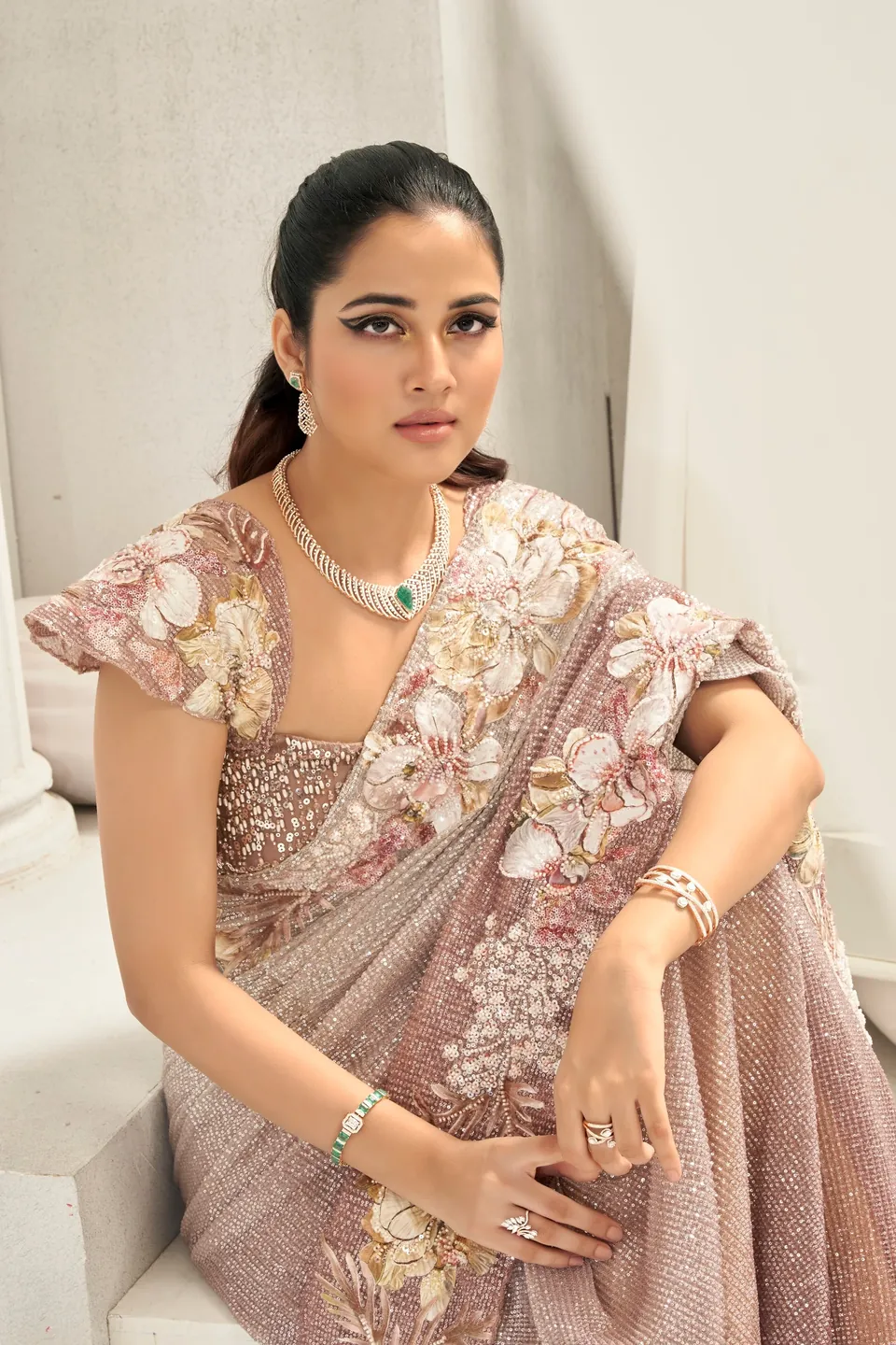 Seated portrait in mauve florals with a diamond necklace and watch