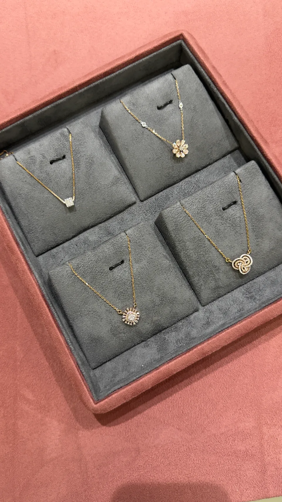 A grey velvet tray of four pendants on fine chains
